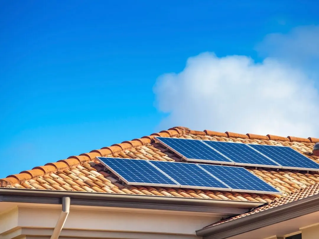 Solar panels on the tiled roof of a North Brisbane home under a clear blue sky